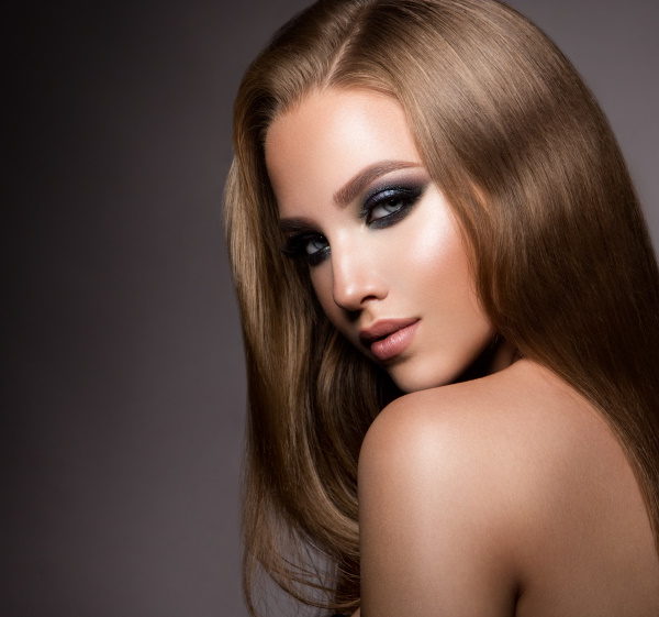 Glamour portrait of beautiful girl model with makeup and romantic hairstyle. Fashion shiny highlighter on skin, sexy gloss lips make-up and dark eyebrows.